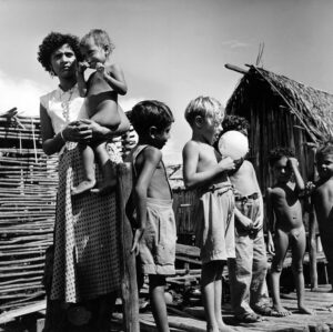 Sin título [Una mujer sostiene un niño en sus brazos acompañada de un grupo de niños]